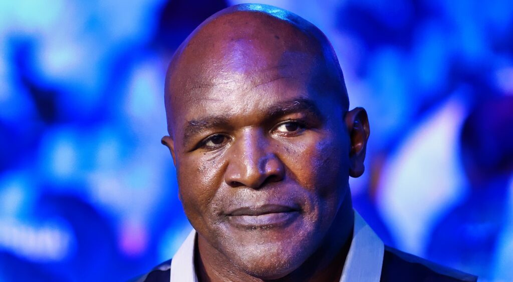 Evander Holyfield looks on while watching a boxing match.