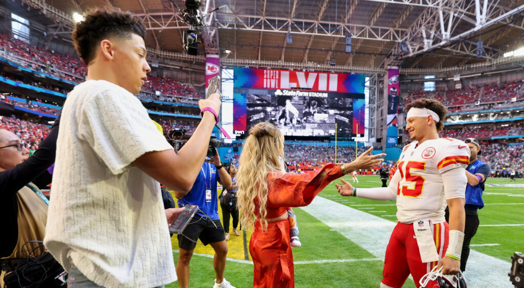 Patrick Mahomes about to embrace Brittany Mahomes whille Jackson Mahomes holds up cell phone