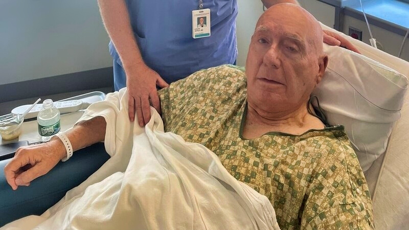 ESPN broadcaster Dick Vitale lying in hospital bed with doctor by his side.