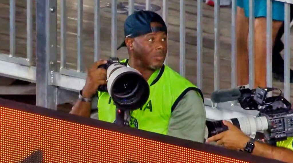 Ken Griffey Jr. holding camera during MLS game.
