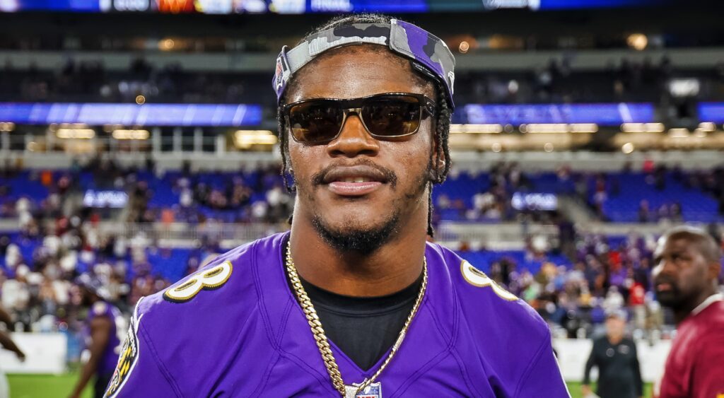 Lamar Jackson looks on while wearing sunglasses and a chain.