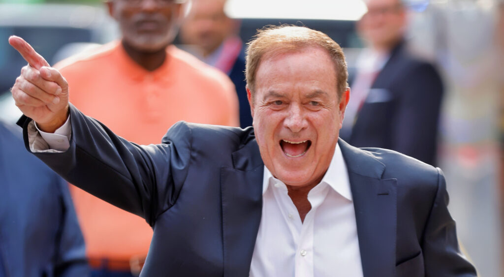 Al Michaels with a hand in the air