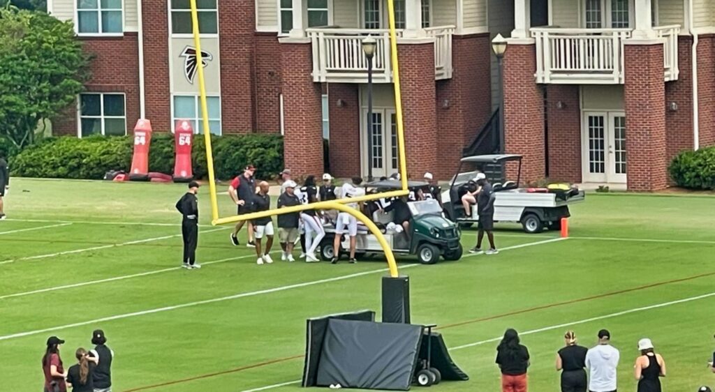 Falcons players around a cart at practice.