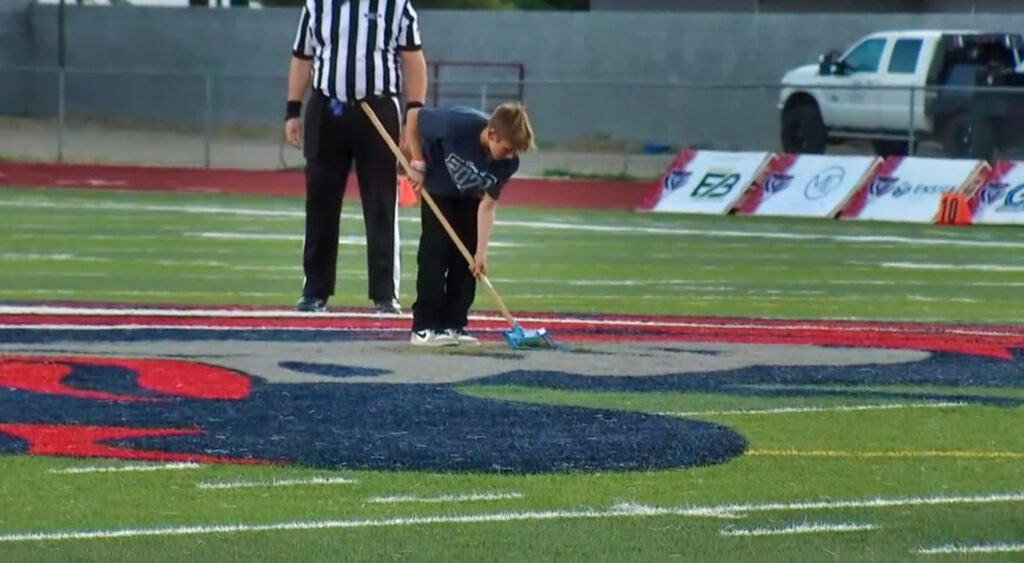 kid using plastic shovel on football field