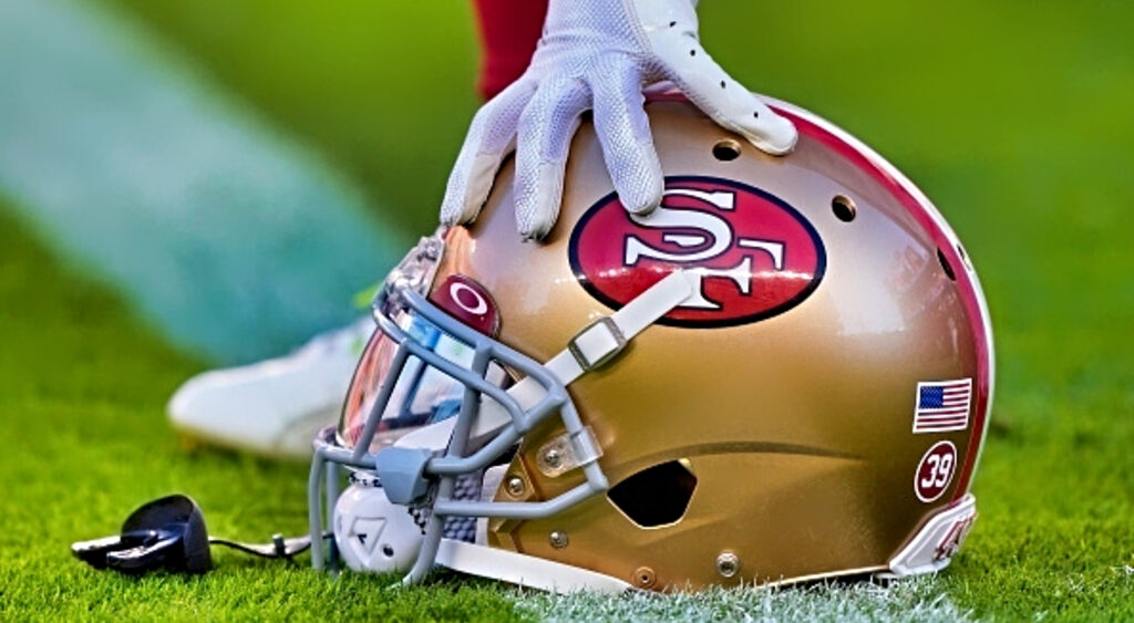 49ers helmet with players hand on it.