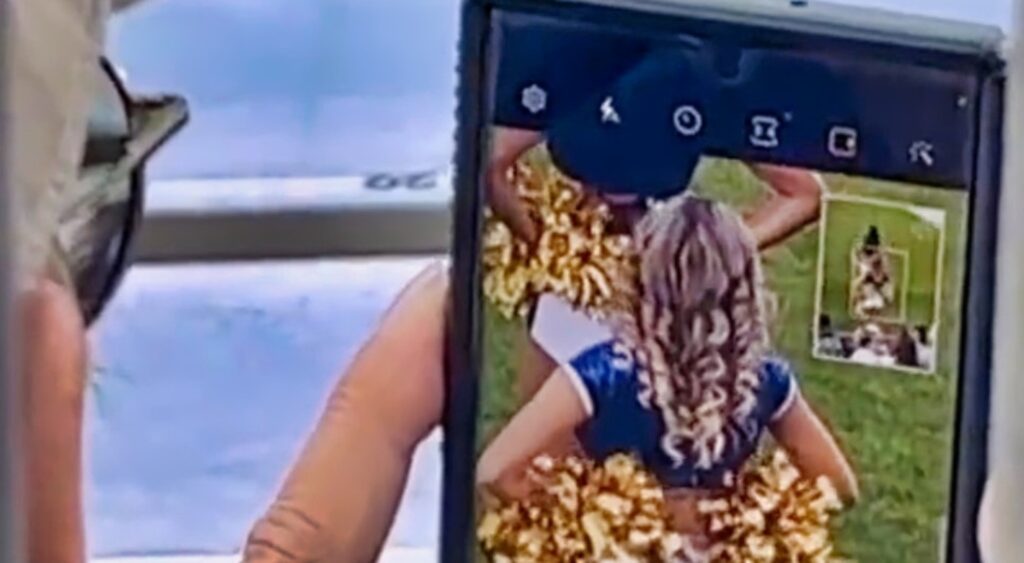 Man caught snapping photos of cheerleader's behind.