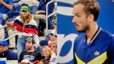 Female tennis fan holding drink and photo of Daniil Medvedev staring at crowd