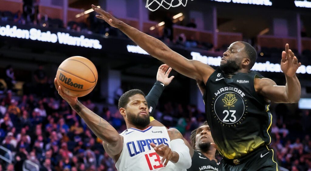 Paul George (left) trying to get ball by Draymond Green (right).