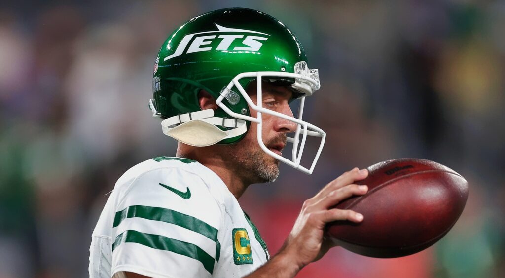 Aaron Rodgers looks on while holding  a ball.