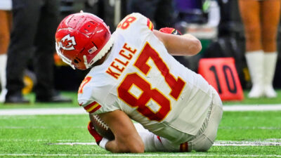 Travis Kelce holding a football on the ground