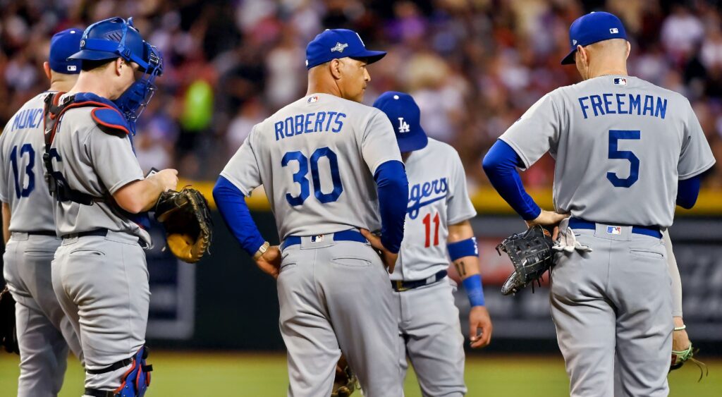 Los Angeles Dodgers' players and manager Dave Roberts meeting on mound.