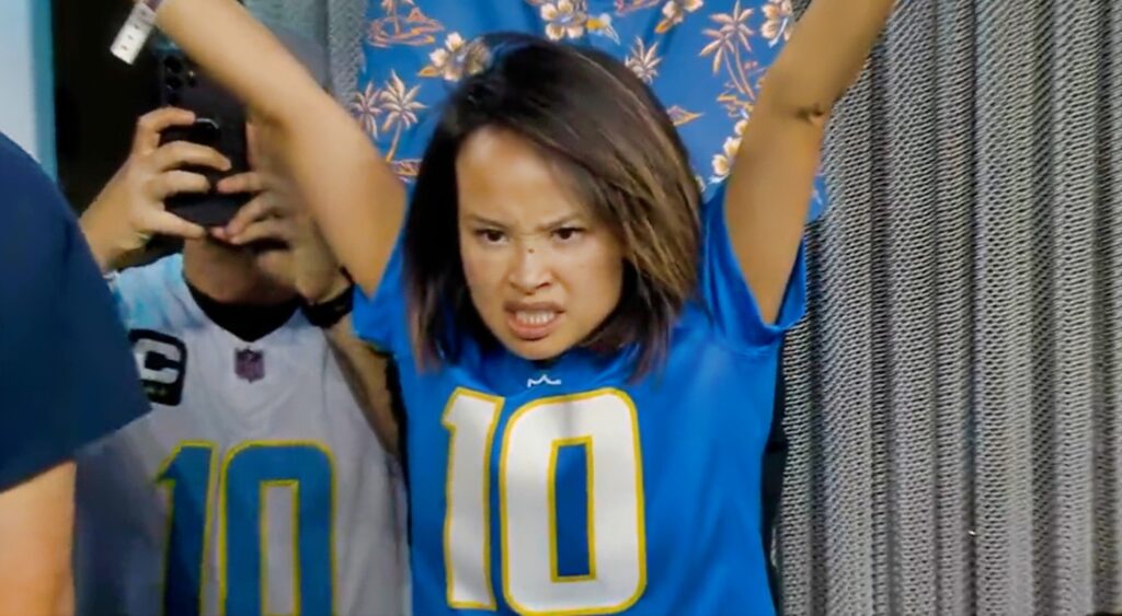 Female Chargers fan with arms up