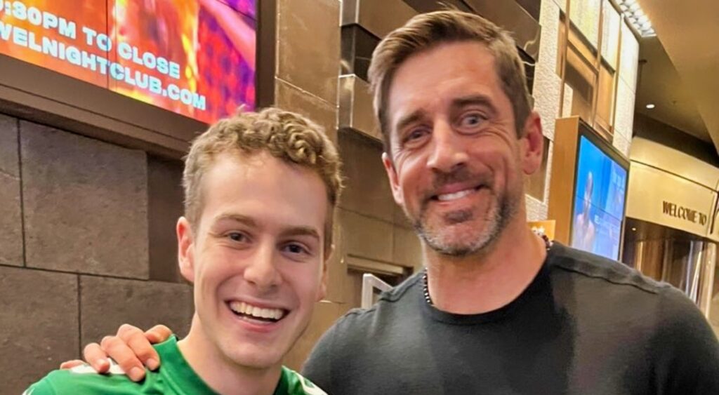 Aaron rodgers takes a photo with a JEts fan.