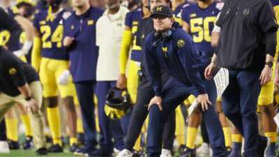 Jim Harbaugh with his hands on his knees