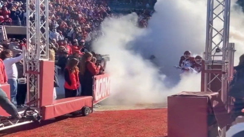 Oklahoma Sooners football team running through smoke for pregame entrance.