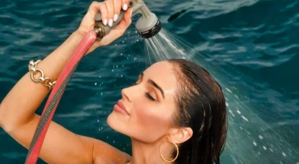 Olivia Culpo spraying herself with water hose