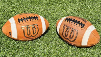 Two Wilson footballs on grass