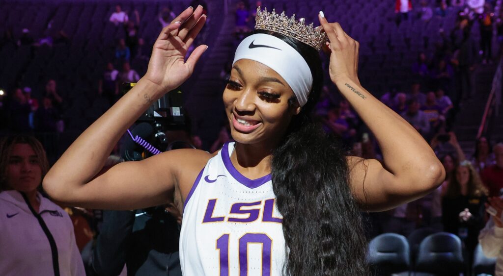 Angel reese in uniform while putting crown on her head.