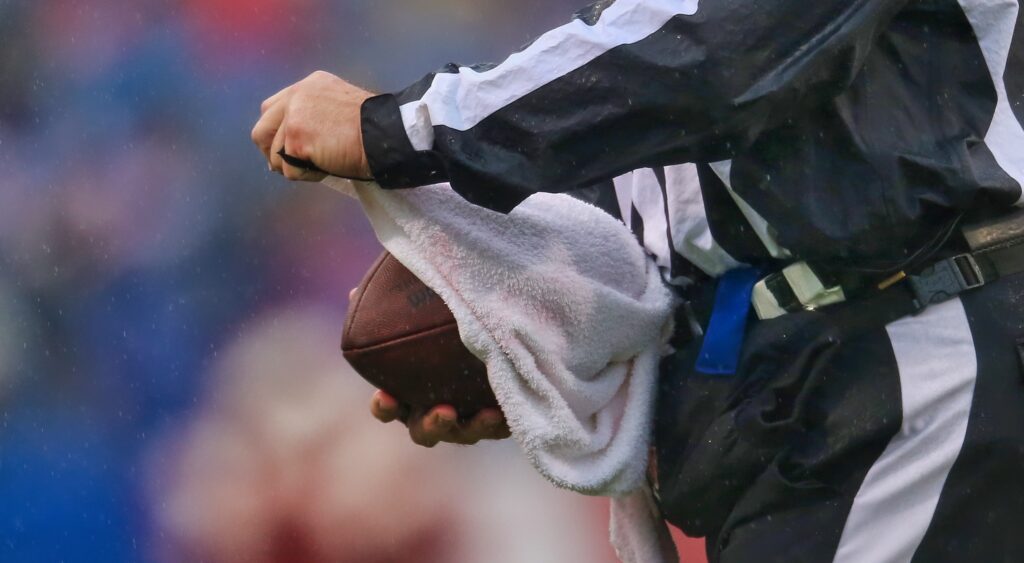 Referee cleans a football with a towel.