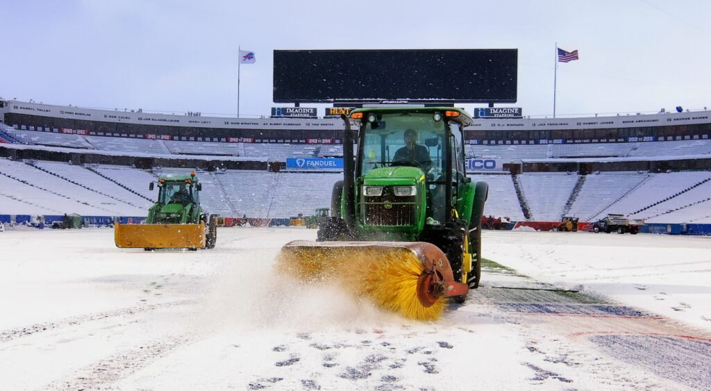 NFL stadium workers clearing snow off the field.