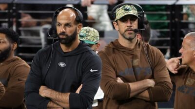 Robert Saleh and Aaron Rodgers standing with arms folded on sidelines