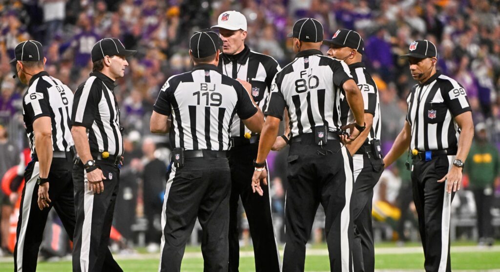 NFL referees talking after penalty.