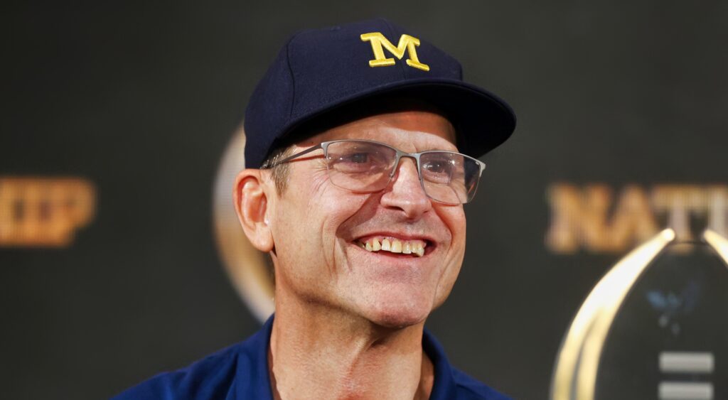 Michigan head coach Jim Harbaugh smiling at press conference.