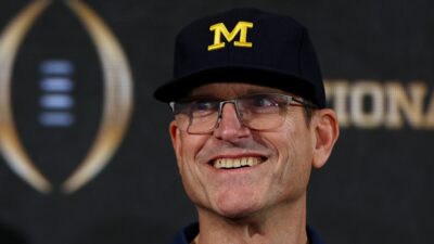 Jim Harbaugh smiling in Michigan cap.
