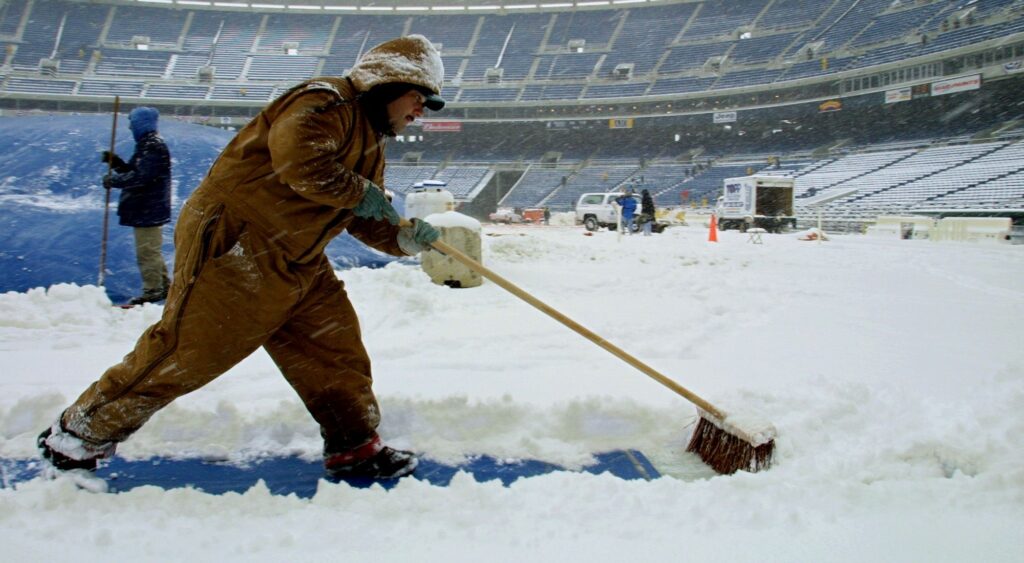 worker clears the snow at NFL field.