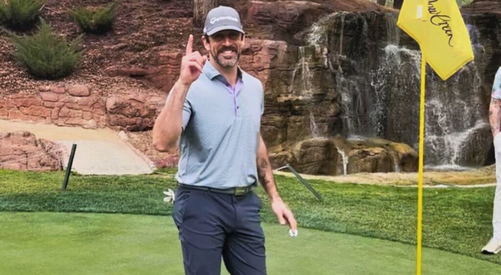 aaron rodgers on golf course holding up one finger