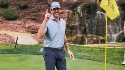 aaron rodgers on golf course holding up one finger