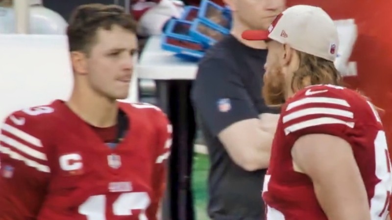 George Kittle (right) speaking to Brock Purdy (left) on sidelines.