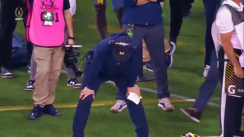 Michigan Wolverines head coach Jim Harbaugh bending over on sidelines.