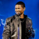 Usher performing on stage wearing black jacket