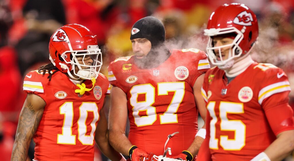 Isiah Pacheco (left), Travis Kelce (middle)  and Patrick Mahomes (right) standing on field.
