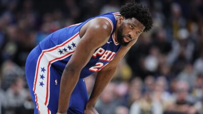 Joel Embiid in 76ers jersey with his hands on his knees