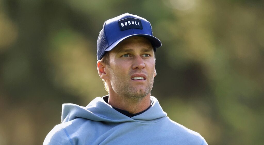 Tom Brady looking on during golf event.