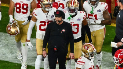 Kyle Shanahan standing in frontof 49ers players