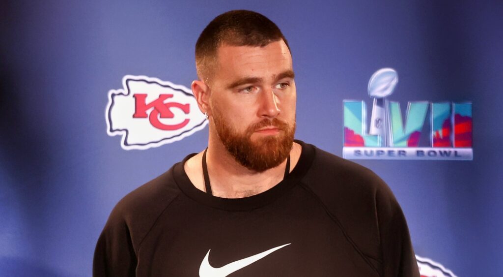 Travis Kelce speaking to reporters with Nike shirt on.