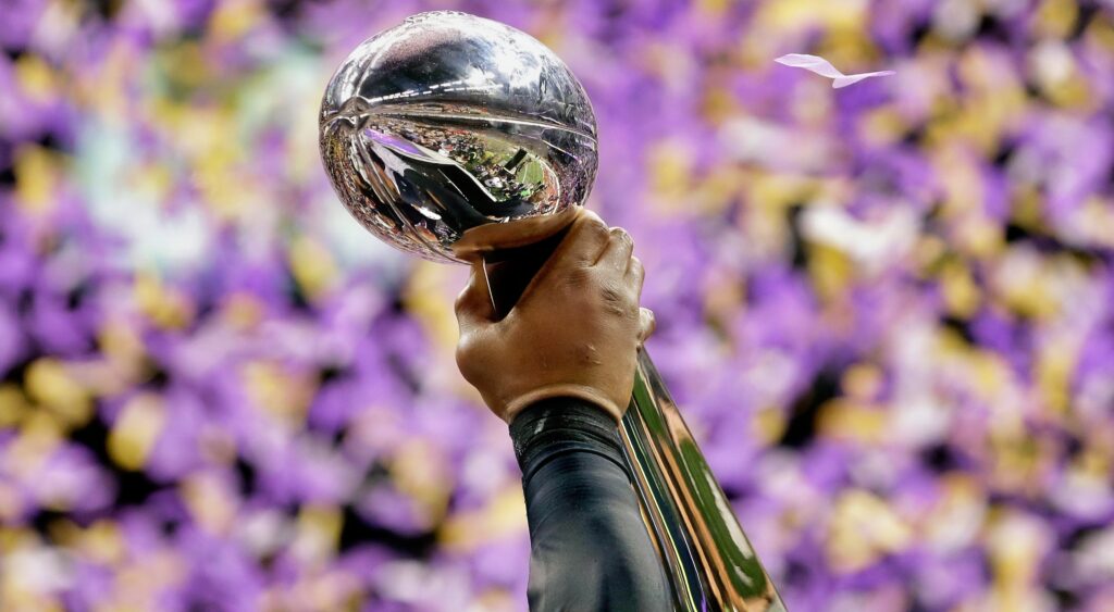 NFL champion lifts the Vince Lombardi Trophy with one hand.