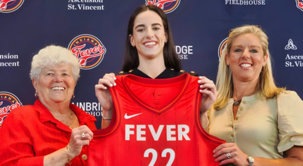 Caitlin Clark holds up her Indiana Fever jersey at his intro press conference.
