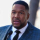 Michael Strahan speaking into a mic