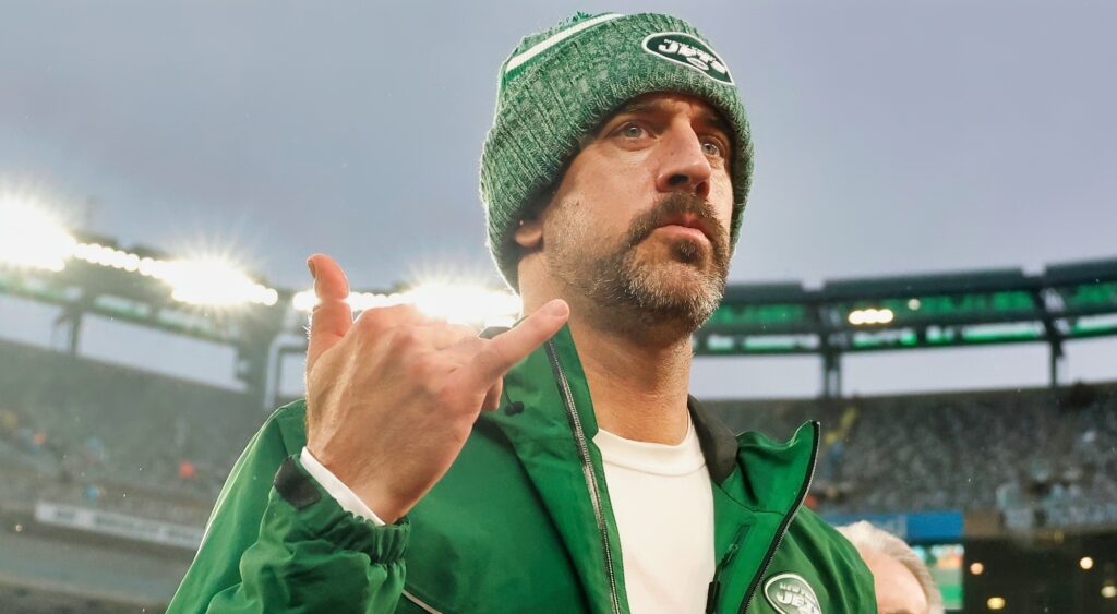Aaron Rodgers throws up a sign while walking off the field.