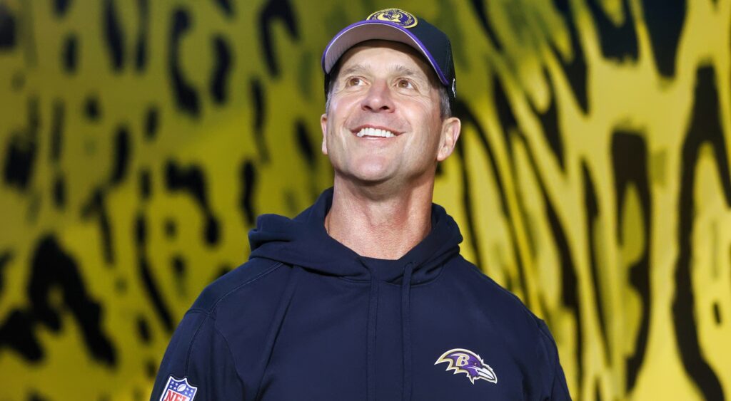 John Harbaugh looks up and smiles while walking onto the field for a game.