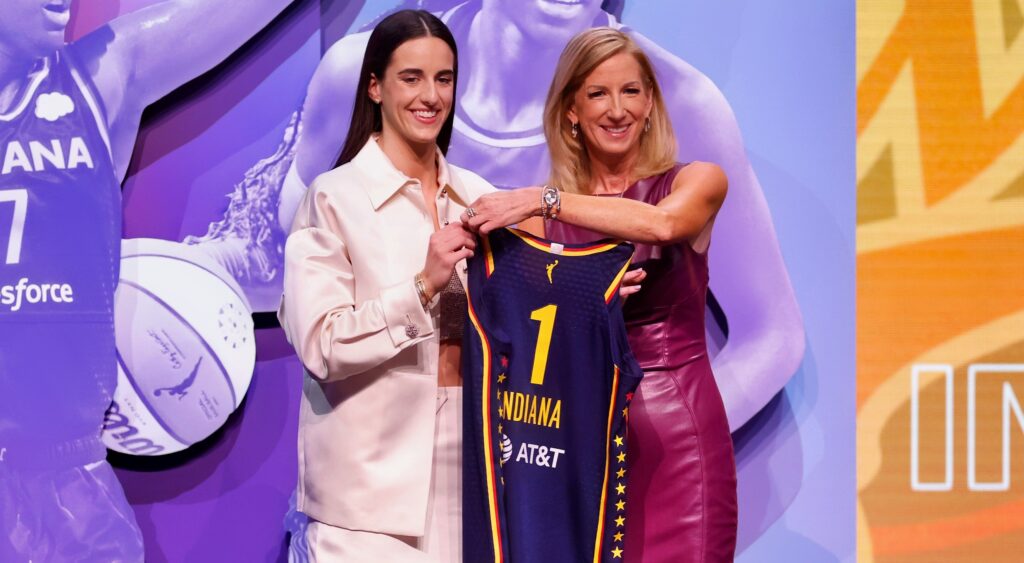 Caitlin Clark holding up jersey at the WNBA Draft