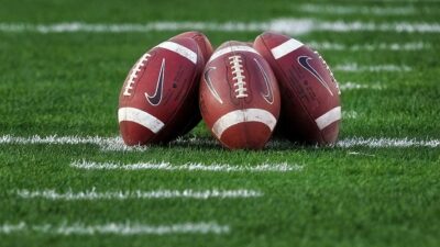 Three College footballs on field