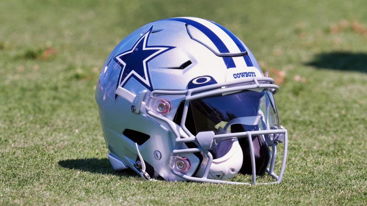 A Dallas Cowboys helmet with Oakley visor sits on the field