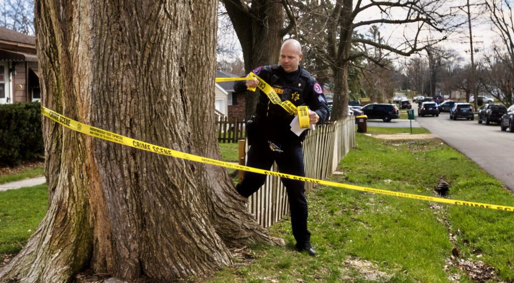 Cop putting police tape around a tree (Not related to arrest of Jonathan Castelan)
