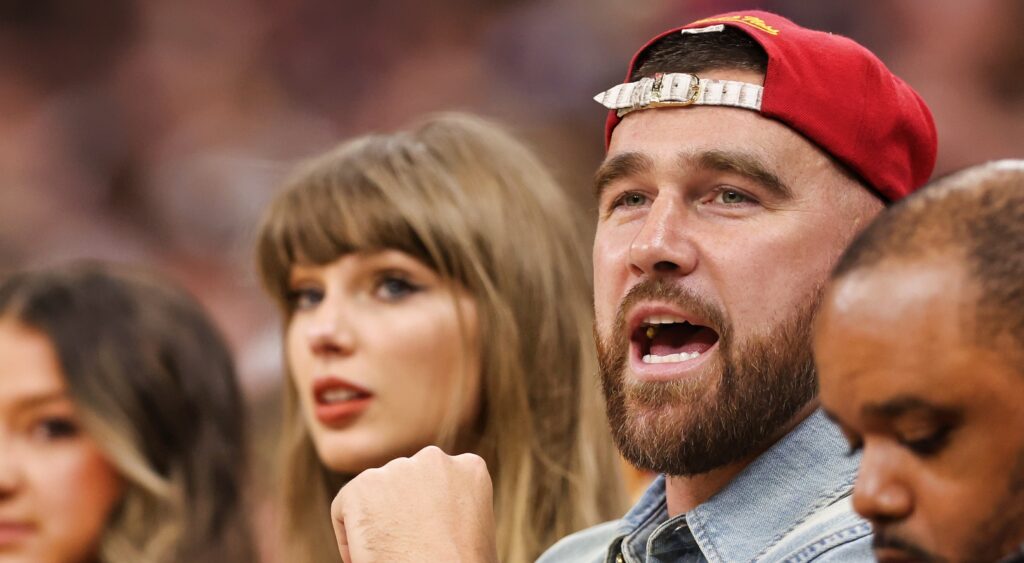 Travis Kelce and Taylor Swift sitting on the sidelines.