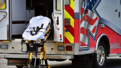 An empty stretcher and an ambulance.